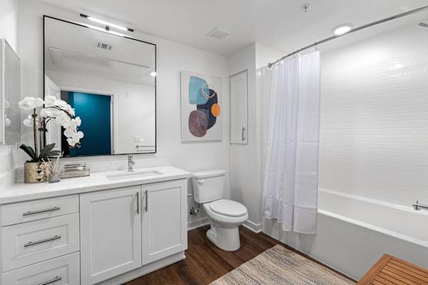 a bathroom with white cabinets and a white toilet and shower